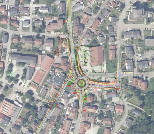 Das Bild zeigt eine Satellitenansicht einer Straßenkreuzung mit verschiedenen überlagerten farbigen Linien und Markierungen, die vermutlich Verkehrsflüsse oder Planungsdaten darstellen.