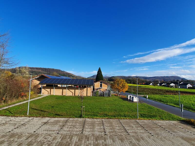 große Wiese zwischen Bauhof und Feuerwehrhaus bei blauem Himmel, Bauplatz für künftige Holzhackschnitzelanlage