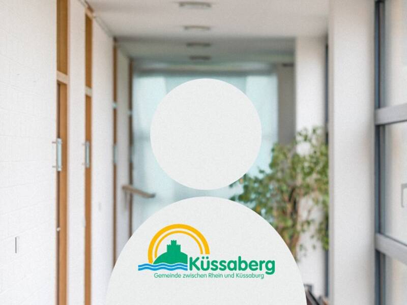 Eine weißes Menschenähnliches Abbild mit dem Logo von Küssaberg in dem langen hellen Flur