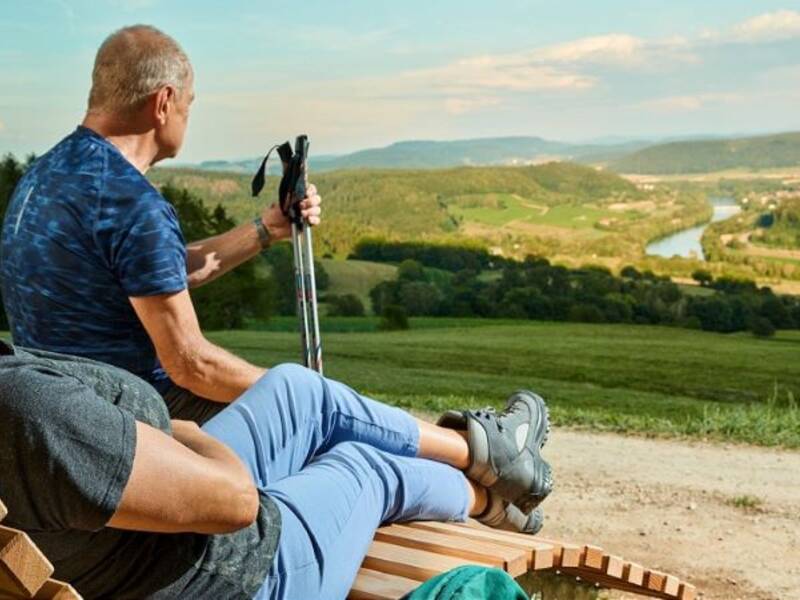 Ein Wanderpärchen sitzt auf einer Himmelsliege und schaut von den Weinbergen aus ins Rheintal